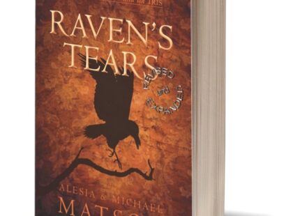 A copy of the book titled "Raven's Tears," the first epic romantasy novel in the Raven & Iris series. The book stands upright. Its cover features a raven silhouette on a warm golden orangey background.