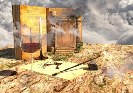 A surreal depiction of classic fantasy elements---an upright open book with stairs leading up to a page, a bubbling potion in a wine glass, a couple of antique keys, and a quill pen with an ink pot---on a wooden tabletop, set as a horizon against a cloudy sky.
