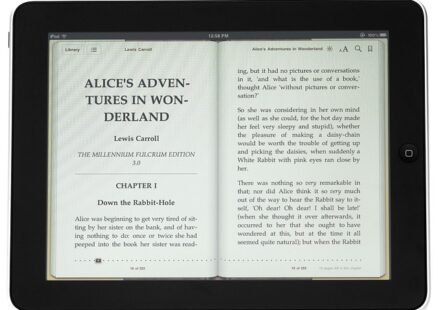 An ebook reader with an image of the print version of "Alice in Wonderland" open on the screen. Apple Books vs Amazon KDP? Either way, it's a rollicking good story!