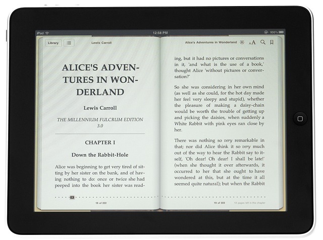 An ebook reader with an image of the print version of "Alice in Wonderland" open on the screen. Apple Books vs Amazon KDP? Either way, it's a rollicking good story!