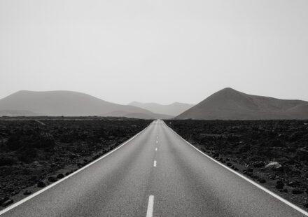 A long two-lane road stretches from the foreground to the mountains in the distance. It symbolizes the long road to an indie author book launch.