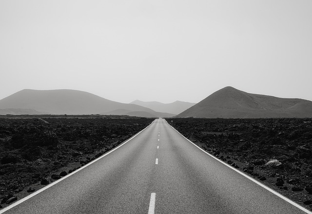 A long two-lane road stretches from the foreground to the mountains in the distance. It symbolizes the long road to an indie author book launch.